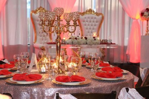 Round wedding table with gold, red and crystal decorations and dinnerware with 2 throne-like chairs in the background, 660 LaFayette Street Horton Events Downtown Nashville