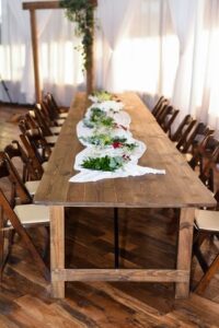 Long wooden table with wedding decor down the center, a wedding arch and full length windows in the background at 660 LaFayette Street, Horton Events Downtown Nashville