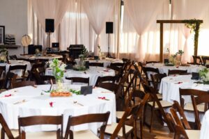 Event hall with decorated round tables and a wedding arch