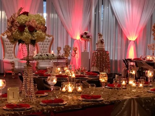 Wedding table with gold, red and crystal decorations and dinnerware with 2 throne-like chairs in the background, 660 LaFayette Street Horton Events Downtown Nashville