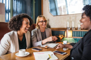 Three ladies with cell phones, planners and coffee cups smiling and laughing. Benefits of hiring a wedding planner, Horton Events Nashville