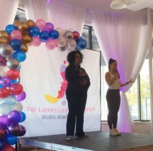 Two ladies on a stage with balloons and a banner, Ladies Lifestyle Affair - Horton Events Downtown Nashville